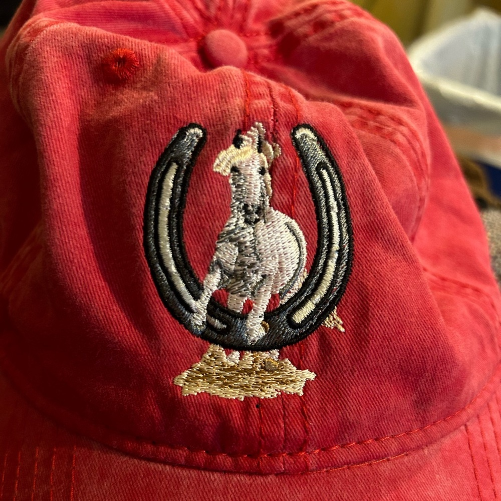 Adjustable cap in red green or black. White horse jumping through horse shoe.